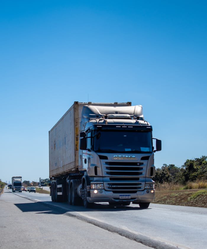A large cargo truck travels on a highway in Brazil under clear blue skies.